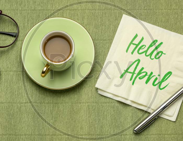 Hello April - Handwriting On A Napkin, Desktop Flat Lay With A Cup Of Coffee And Reading Glasses