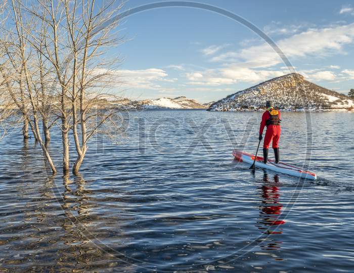 Male Paddler In A Drysuit And Life Jacket Is Paddling A Long Racing Stand Up Paddleboard In Winter Conditions On A Lake In Colorado - Horsetooth Reservoir, Fitness And Training Concept