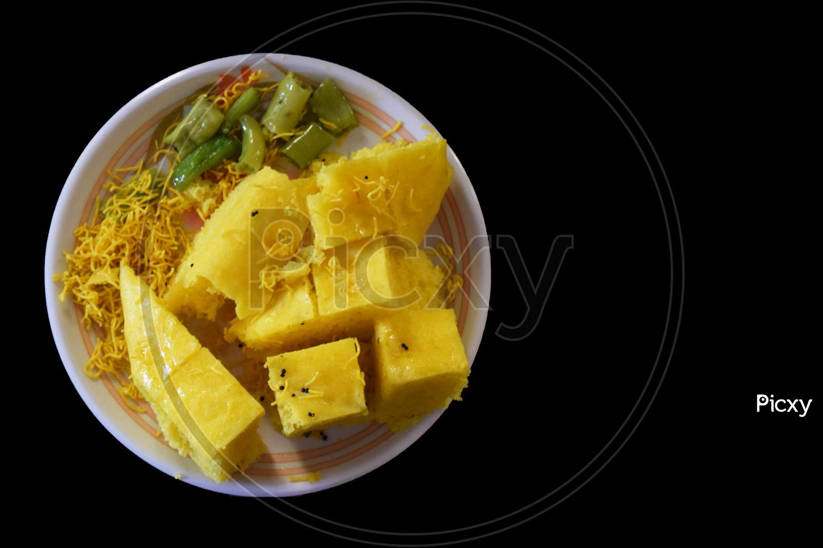 Khaman with sev and mirchi in plate top view with black background