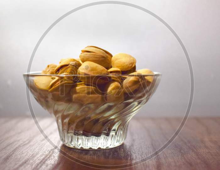 Pistachios pista in glass transparent bowl on wood
