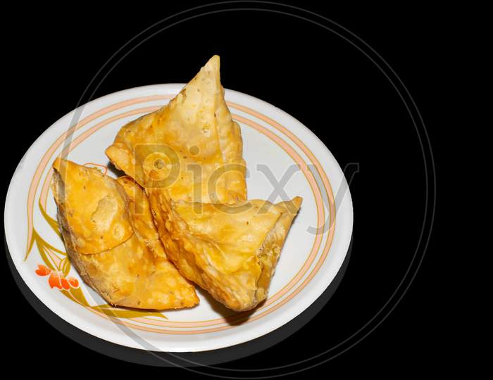 Samosa in plate with black background top view