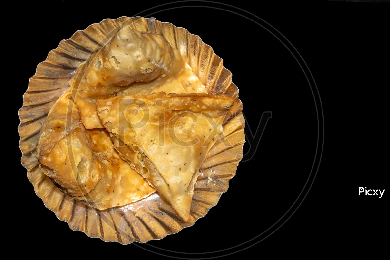 Samosa in plate with black background top view