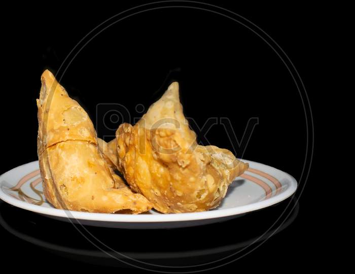 Samosa in plate with black background front view
