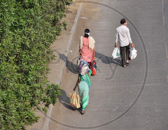 People carrying vegetables and other essentials from a makeshift market under Hitech City MMTS station flyover