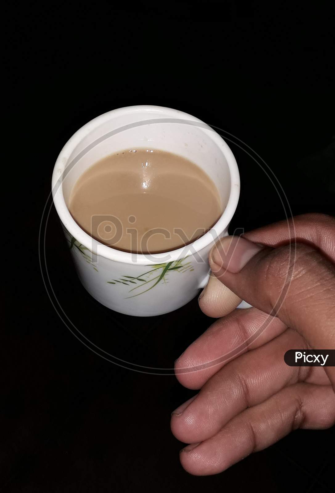A guy is holding tea cup in his hand in black background