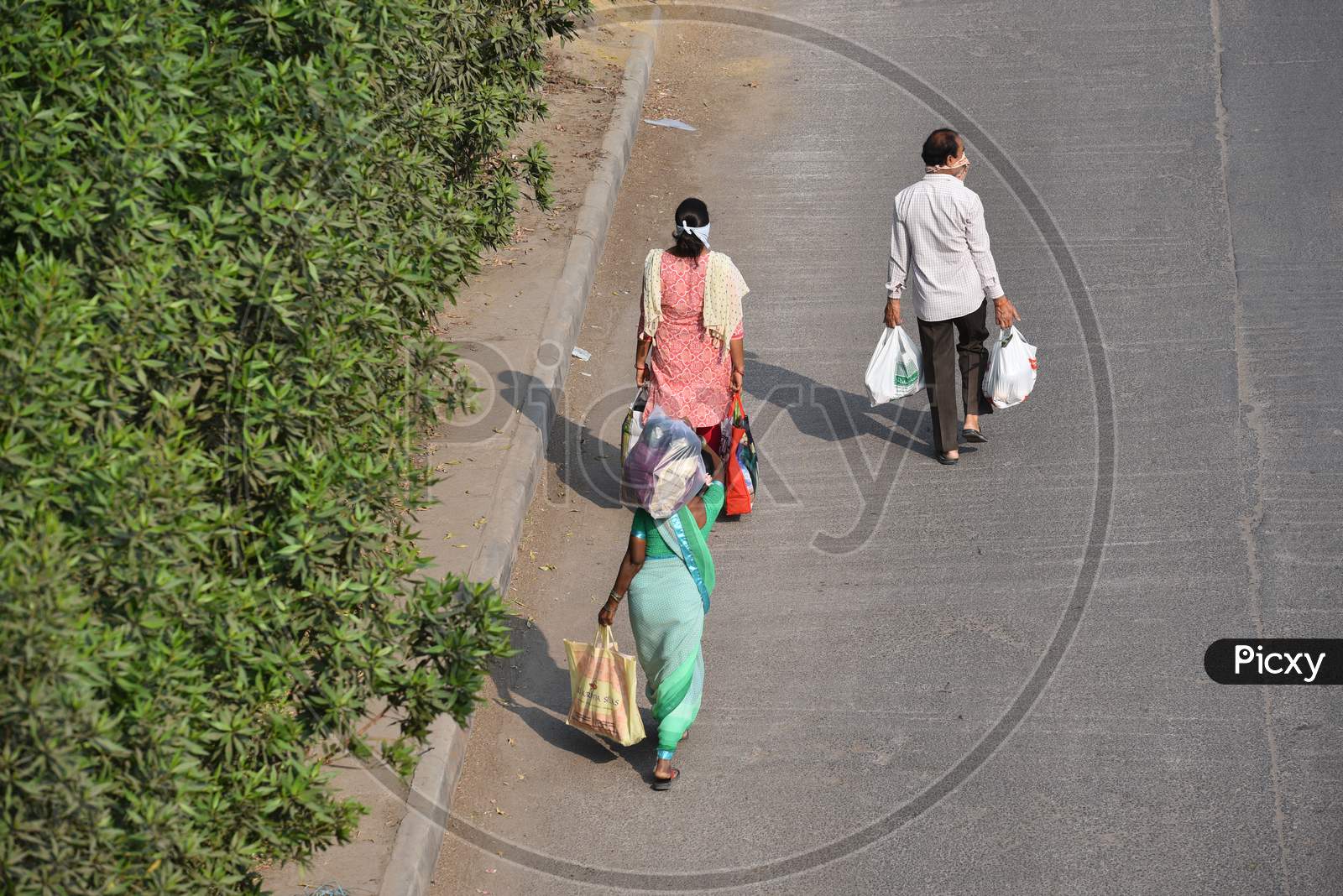 People carrying vegetables and other essentials from a makeshift market under Hitech City MMTS station flyover
