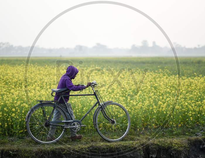 Daily Life. Barpeta, Assam, India. 24 January 2020. A Boy Walking With His Bicycle Next In A Mustard Field, At Kayakuchi Village, In Barpeta District Of Assam On Jan. 24, 2020. Photo: David Talukdar