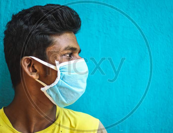 Protection Against Contagious Disease, Coronavirus. Man Wearing Hygienic Mask To Prevent Infection, Airborne Respiratory Illness Such As Flu, 2020. Outdoor Shot Isolated On Blue Background. Asian Young Man Have A Cold And Wearing Blue Mask