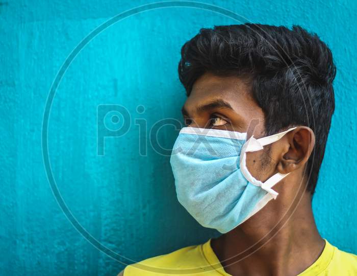 Protection Against Contagious Disease, Coronavirus. Man Wearing Hygienic Mask To Prevent Infection, Airborne Respiratory Illness Such As Flu, 2020. Outdoor Shot Isolated On Blue Background. Asian Young Man Have A Cold And Wearing Blue Mask