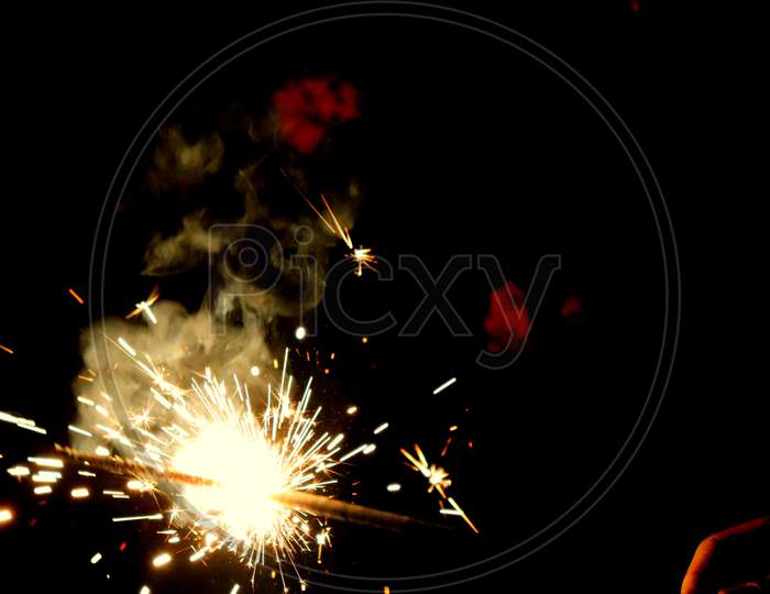 A person holds ignited fireworks during the celebration of Diwali. Have space for text.