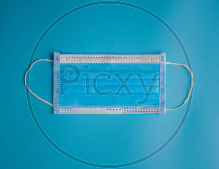 Blue Medical Disposable Face Mask With Covid-19 Printed On It. Covid-19 - Wuhan Novel Coronavirus Pneumonia Gets Official Name From Who: Covid-19. Disposable Breath Filter Face Mask With Earloop