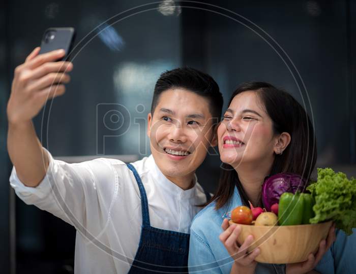 Portrait Of Happy Young Couple Cooking Together In The Kitchen At Home.