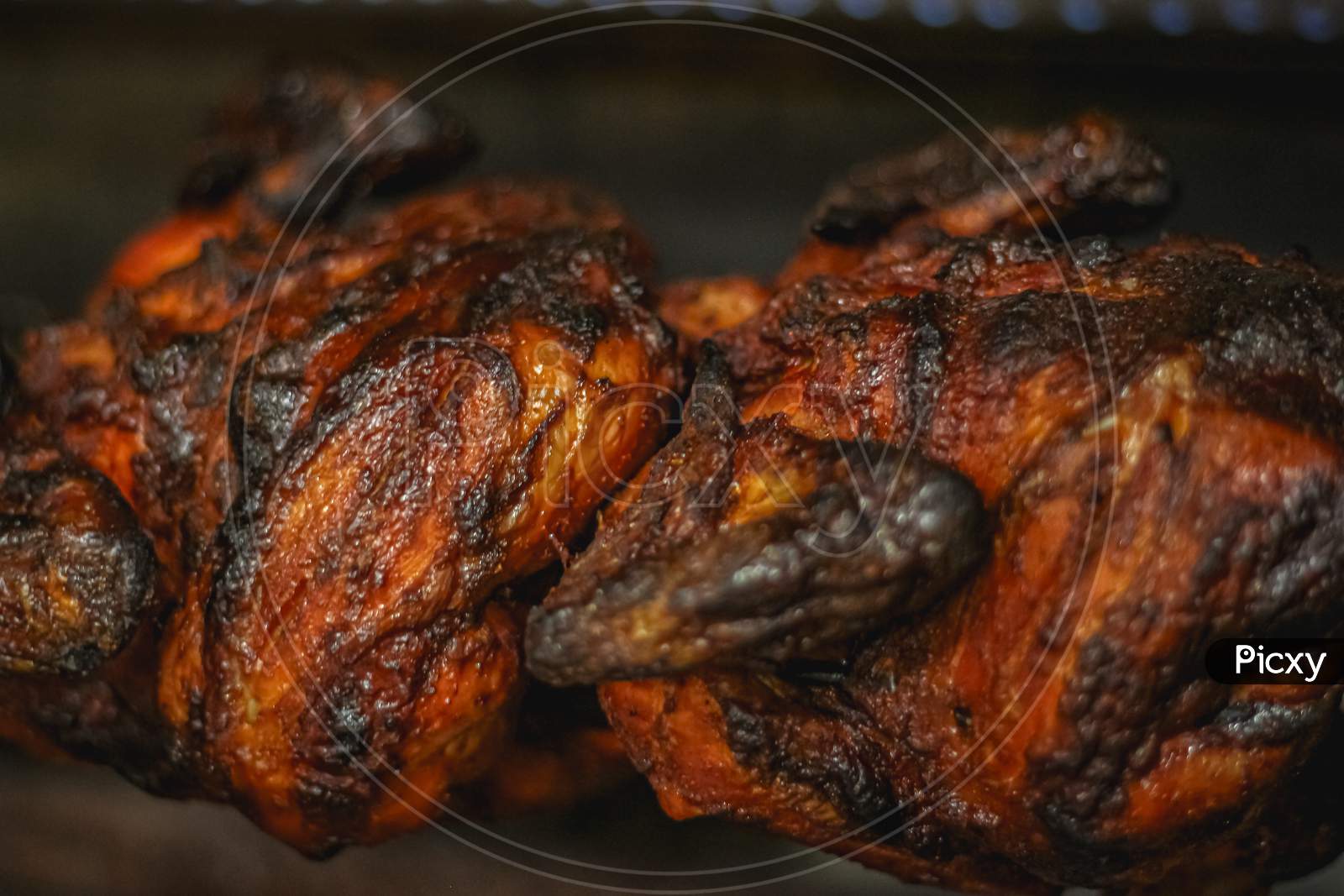 Grilled Chicken Over Open Fire . Closeup Grilled Chicken. Charred Rotisserie Chicken Over Open Flames In A Barbecue.