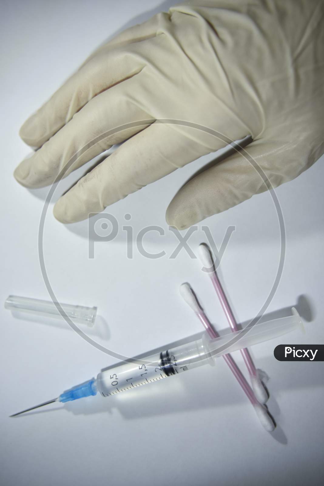 Hand In The Medical Glove And Syringe With Cotton Buds On The White Backgrouns. Medical Issues Concept.