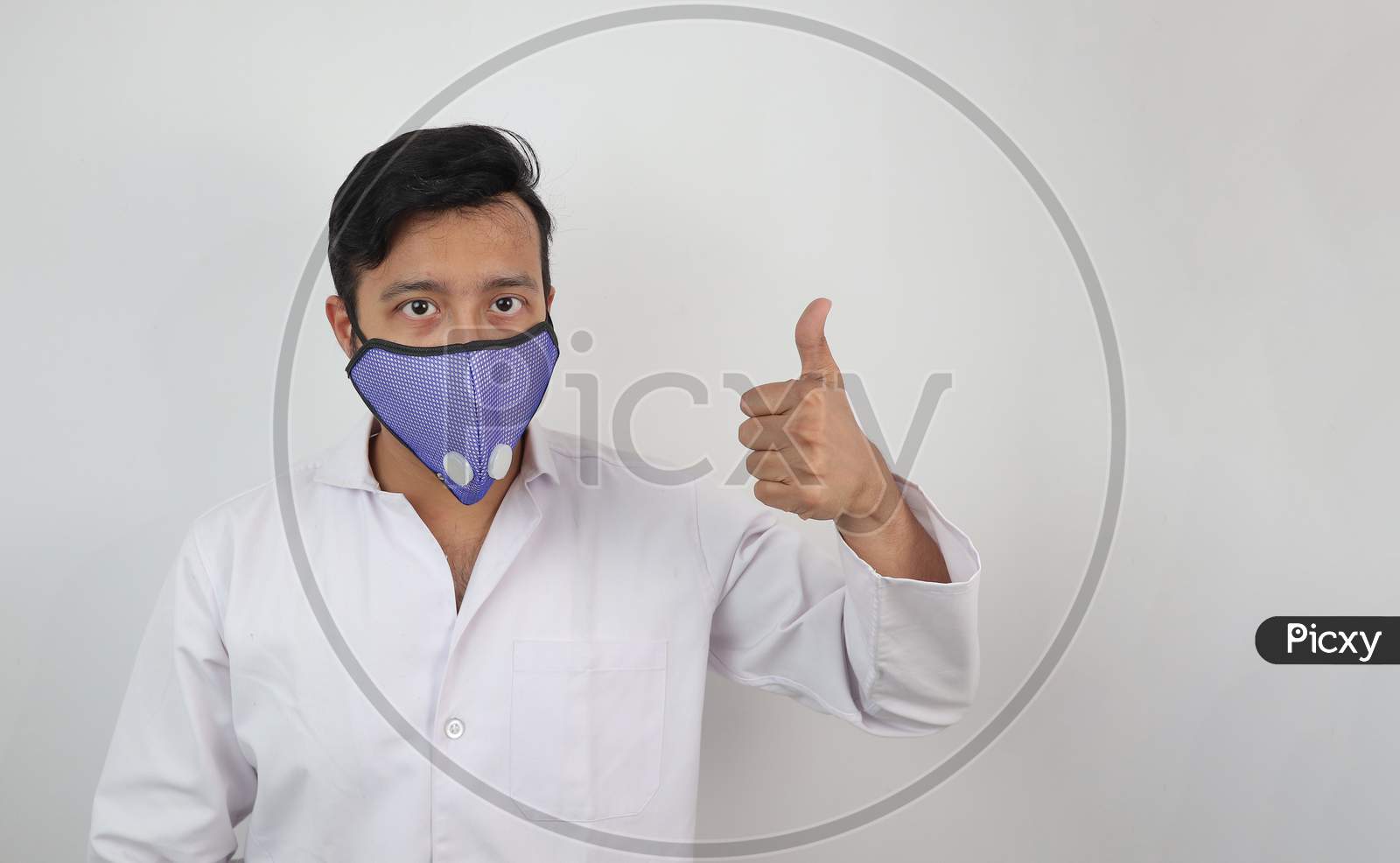 A Medical Professional In White Coat And N 99 Mask With Thumbs Up Positive Expression Isolated In White Background With Space For Text.
