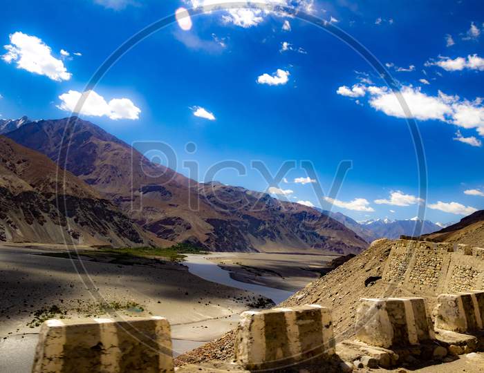 Shades Of Cloud In High Dynamic Range Image Of Barren Mountain In A Desert With River And Deep Blue Sky In Ladakh, Jammu And Kashmir, India
