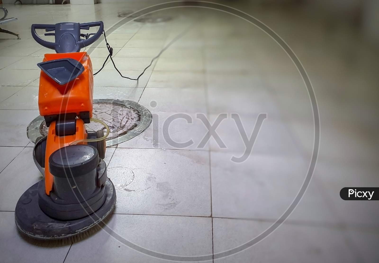 A Motorized Floor Cleaner With Mop On White Granite Marble Floor With Blurred Background.