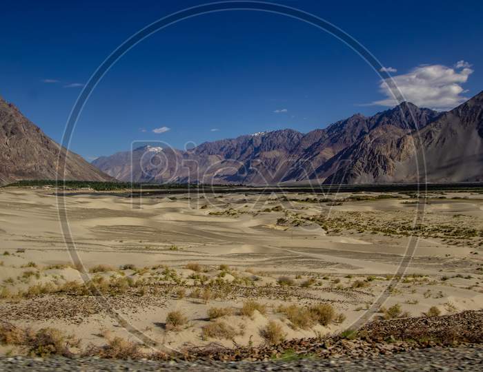 Arid Lands Of Ladakh With Barren Himalayan Peaks Viewable In Distance With Deep Blue Sky.