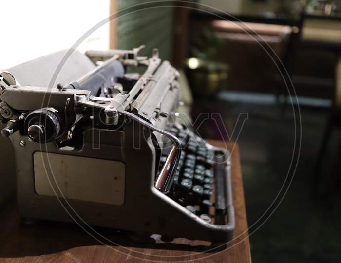 A Closeup Image Of An Old Vintage Type Writer On A Table With Eroded Keys With Selective Focus On The Handle Background Blur