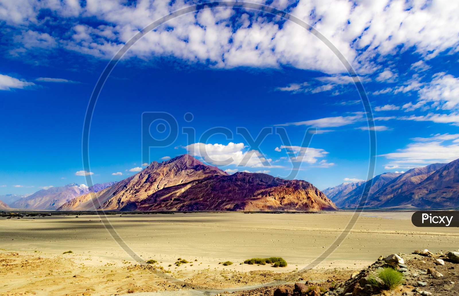 High Dynamic Range Image Of Barren Mountain In A Desert With Deep Blue Sky And White Patchy Clouds In Ladakh, Jammu And Kashmir, India