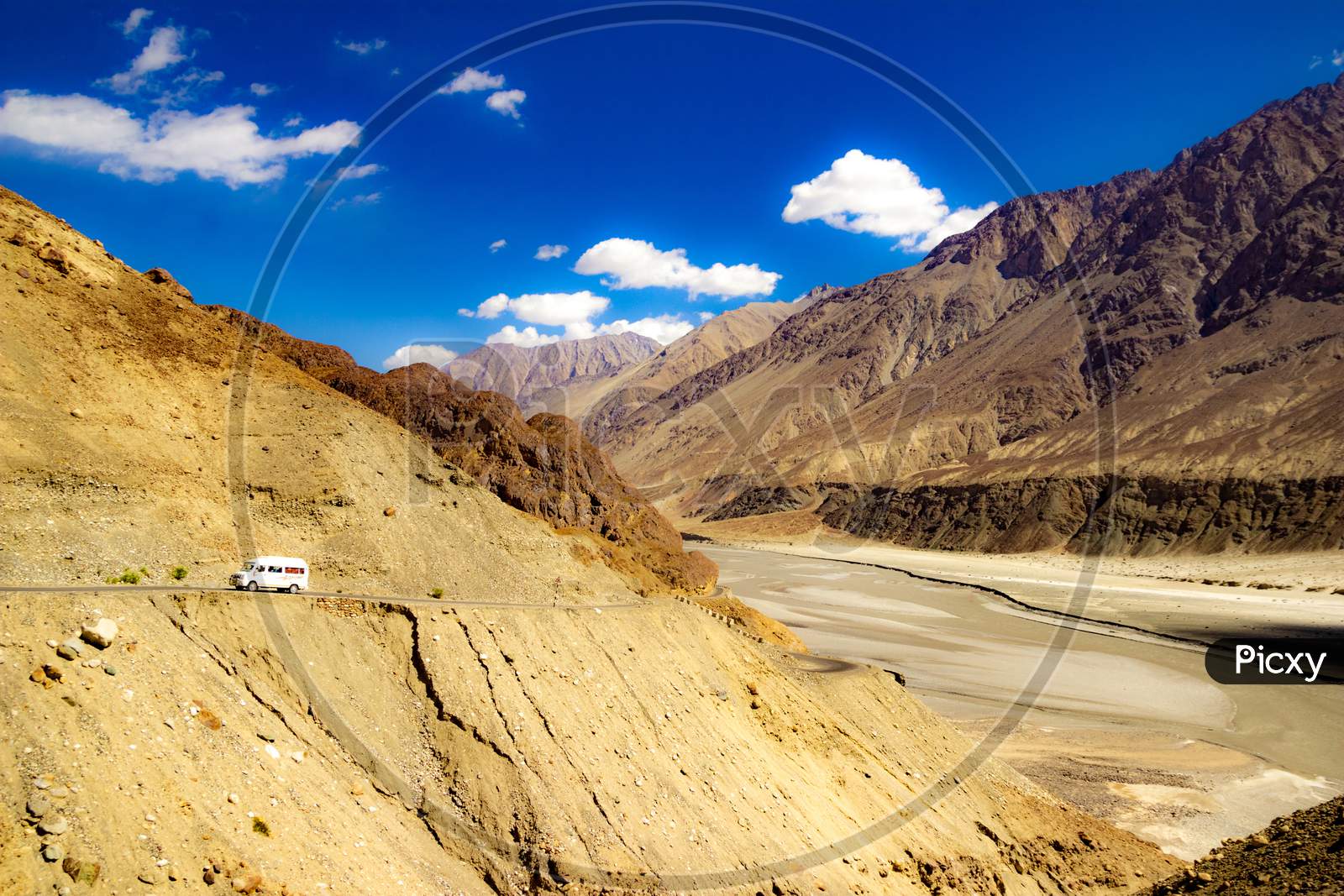 High Dynamic Range Image Of Barren Mountain In A Desert With River And Deep Blue Sky And White Patchy Clouds In Ladakh, Jammu And Kashmir, India