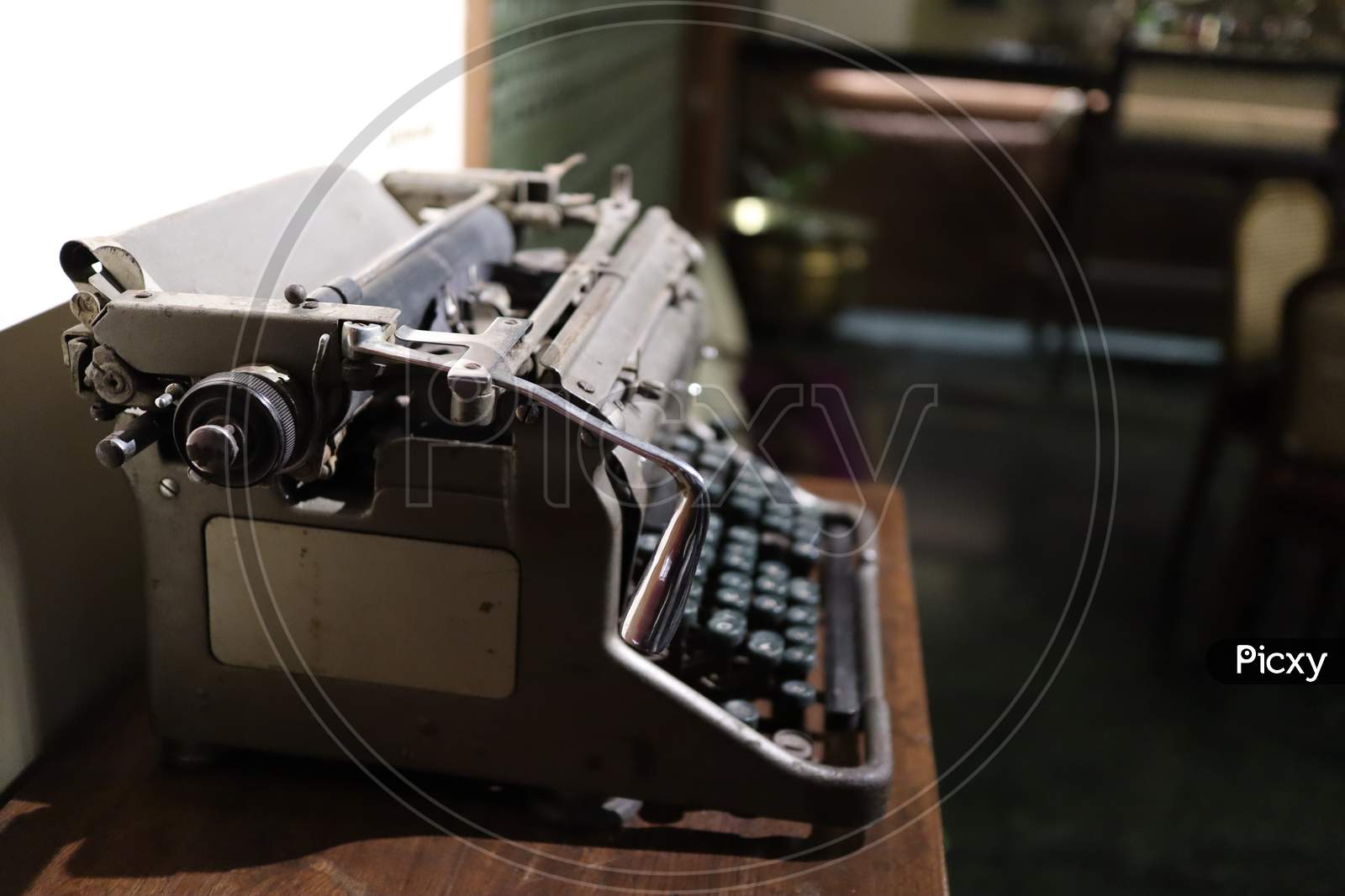 A Closeup Image Of An Old Vintage Type Writer On A Table With Eroded Keys With Selective Focus On The Handle Background Blur