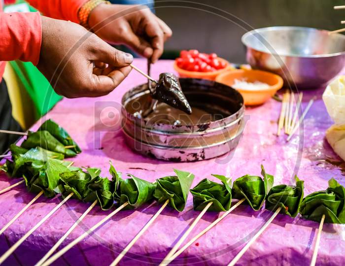 Cone Of Betel Leaf Being Coated With Chocolate Syrup To Form Chocolate Paan With Selective Focus And Blurred Background.
