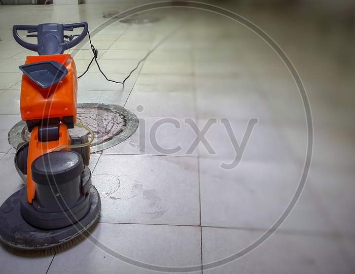 A Motorized Floor Cleaner With Mop On White Granite Marble Floor With Blurred Background.