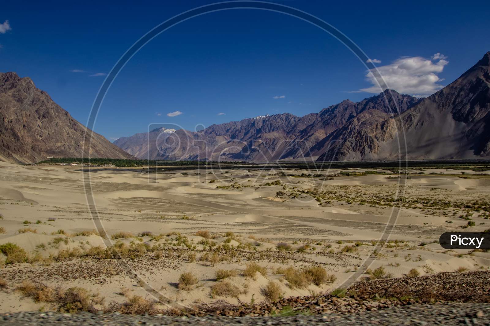 Arid Lands Of Ladakh With Barren Himalayan Peaks Viewable In Distance With Deep Blue Sky.