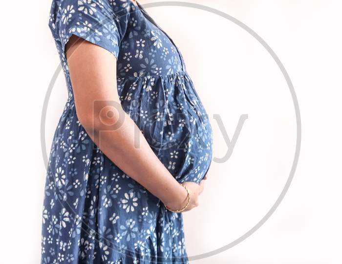 A Pregnant Lady With Blue Dress And Hands On Belly