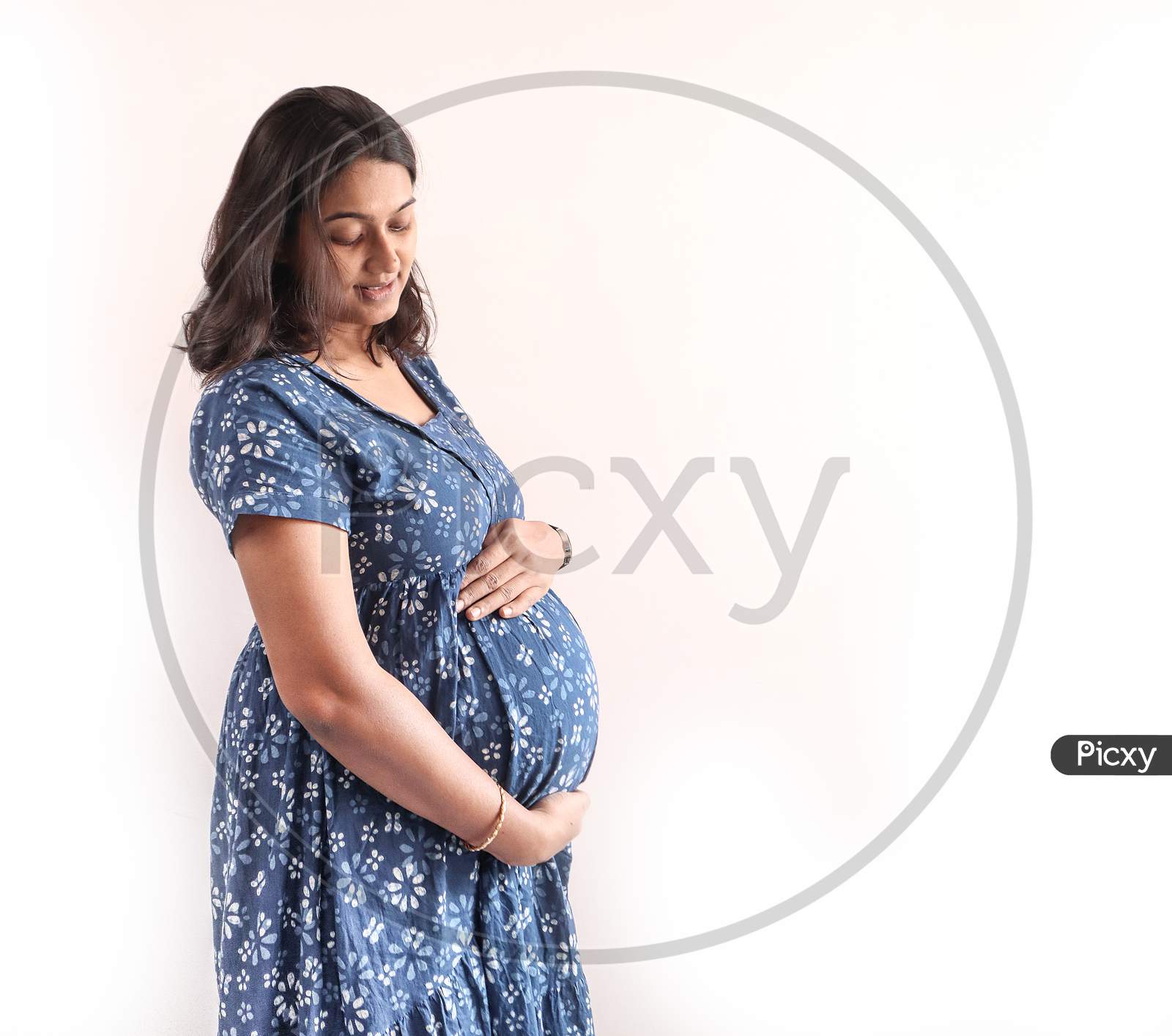 A Pregnant Indian Lady With Blue Dress And Hands On Belly
