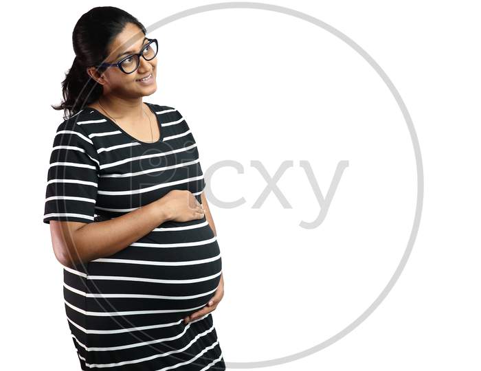 A Pregnant Lady Wearing Spectacles With Black Dress With White Stripes And Hands On Belly Looking Up In Delight With Copy Space For Text.