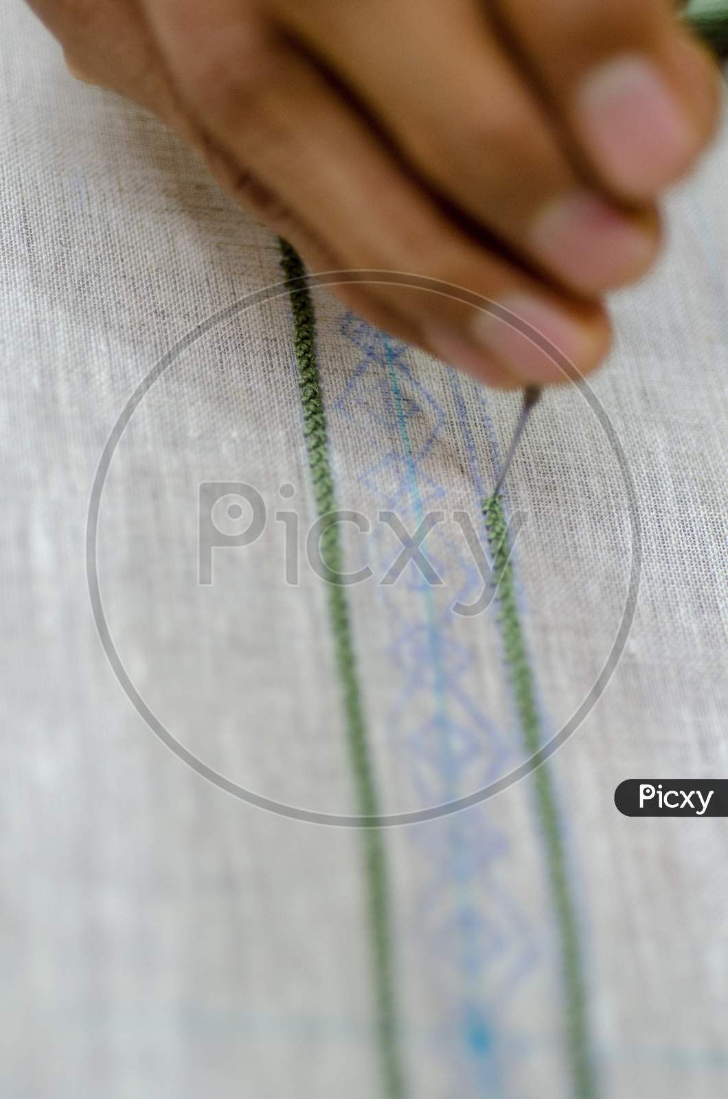 An Embroidery Worker Stitching Design on a Fabric Closeup