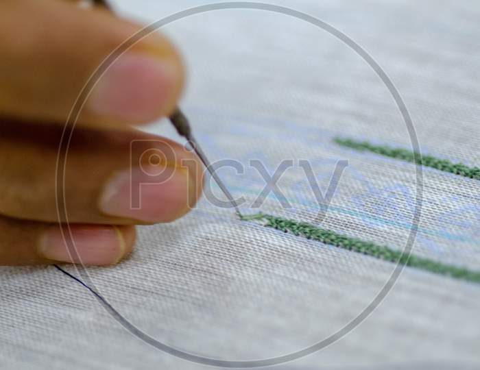 An Embroidery Worker Stitching Design on a Fabric Closeup