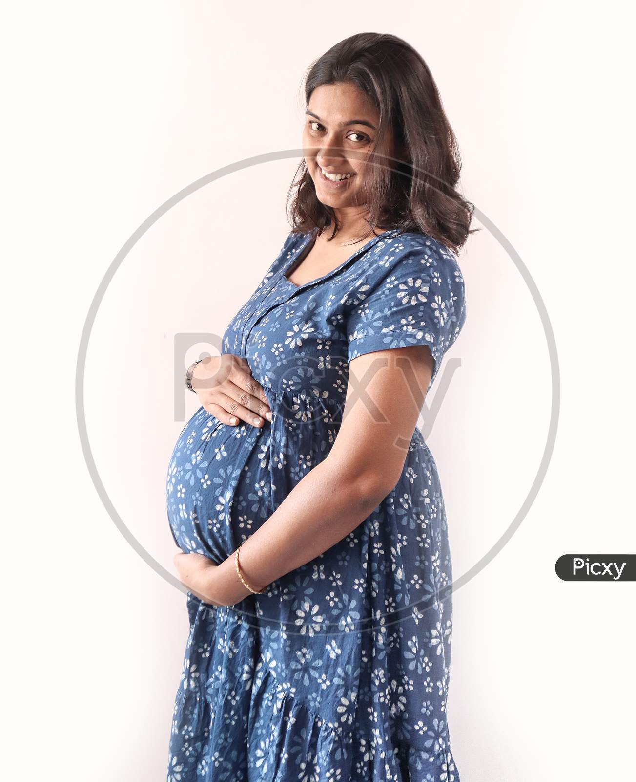 A Pregnant Indian Lady With Blue Dress And Hands On Belly