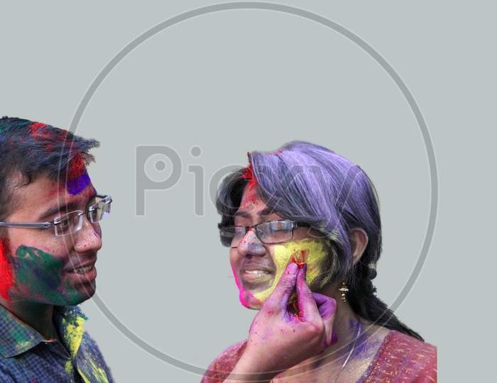 Romantic Couple Applying Colors On The Occasion Of Holi Festival In Isolated Grey Background.