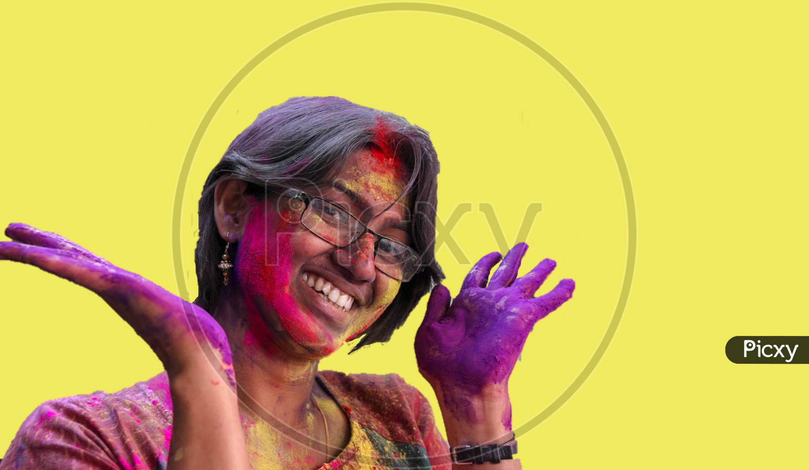 Portrait Of A Young Lady With Holi Colours On Face Smiling At The Camera With Isolated Solid Yellow Background.