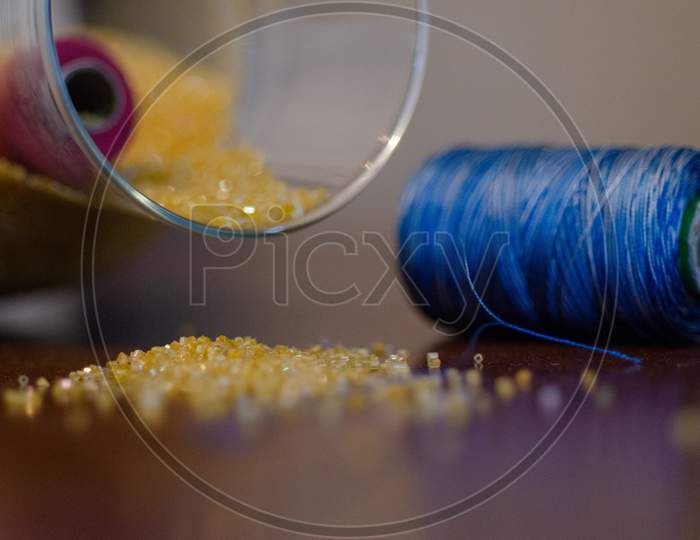 Embroidery Beads And Colourful Sewing Threads On Wooden Table Background