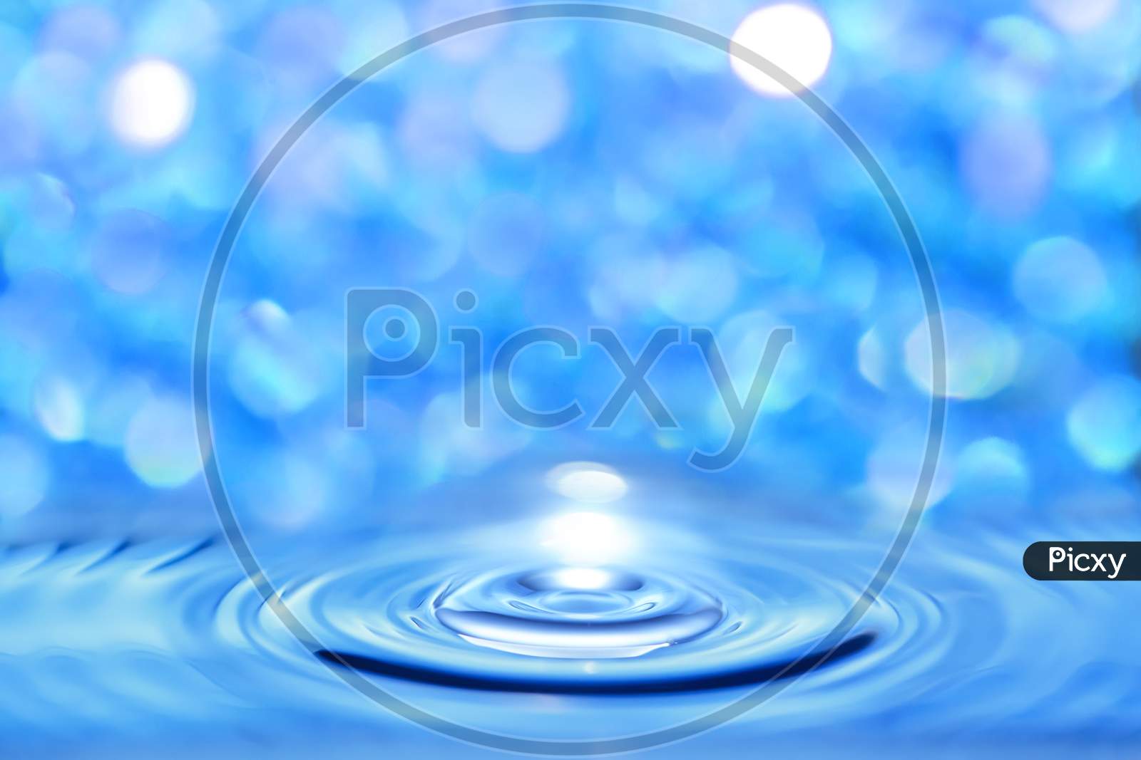 Abstract Water Blue Liquid Crossed By A Circular Wave On A Bright Bokeh Background.