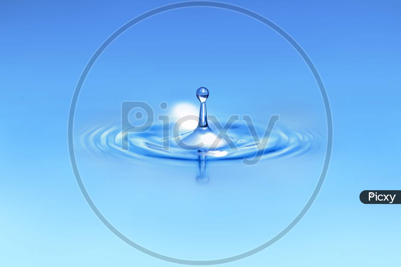 Closeup On Drop Of Water Falling In A Blue Liquid.