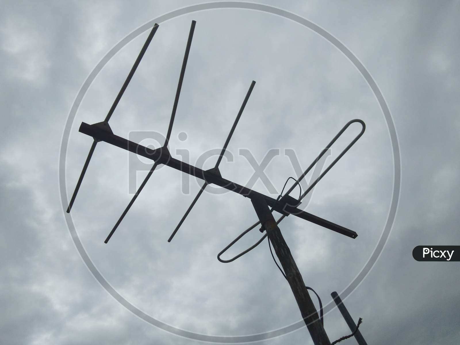 A TV antenna with cloudy sky background