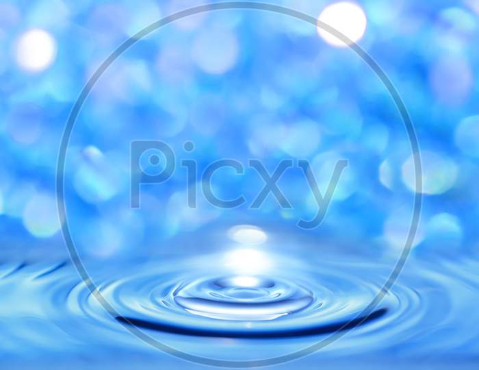 Abstract Water Blue Liquid Crossed By A Circular Wave On A Bright Bokeh Background.