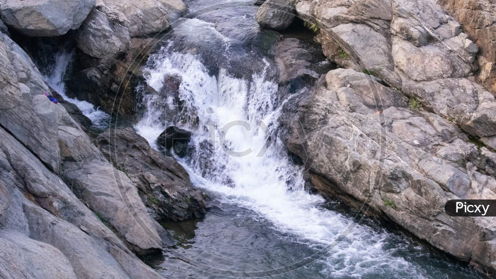 A Waterfall Where Water Is Falling Between The Rocks