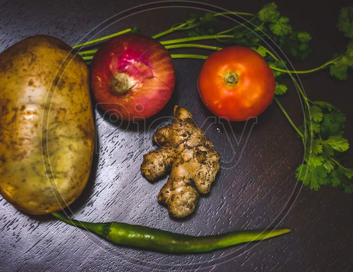 Mixed Vegetables On Wooden Table Top View. Vegetable And Food Photography - Vegetables On Table Potato,Onion,Ginger,Tomato,Coriander Leaf And Chilli