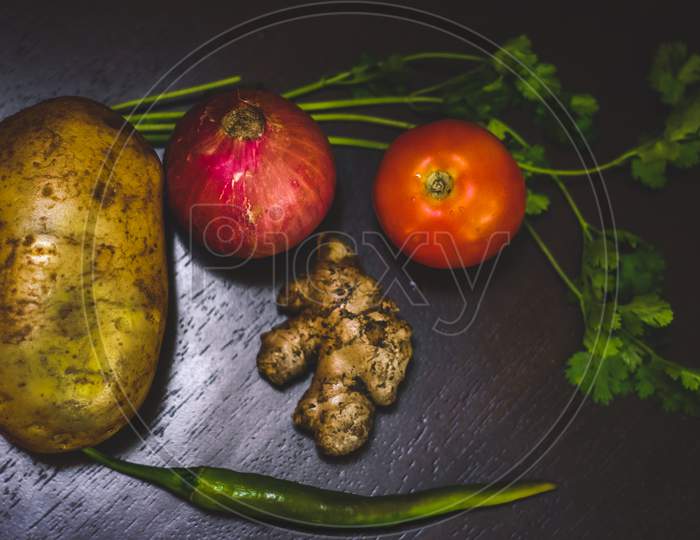 Mixed Vegetables On Wooden Table Top View. Vegetable And Food Photography - Vegetables On Table Potato,Onion,Ginger,Tomato,Coriander Leaf And Chilli