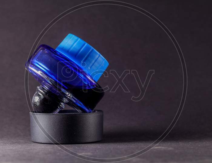 A View Of Closed Blue Ink Bottle Against Black Background