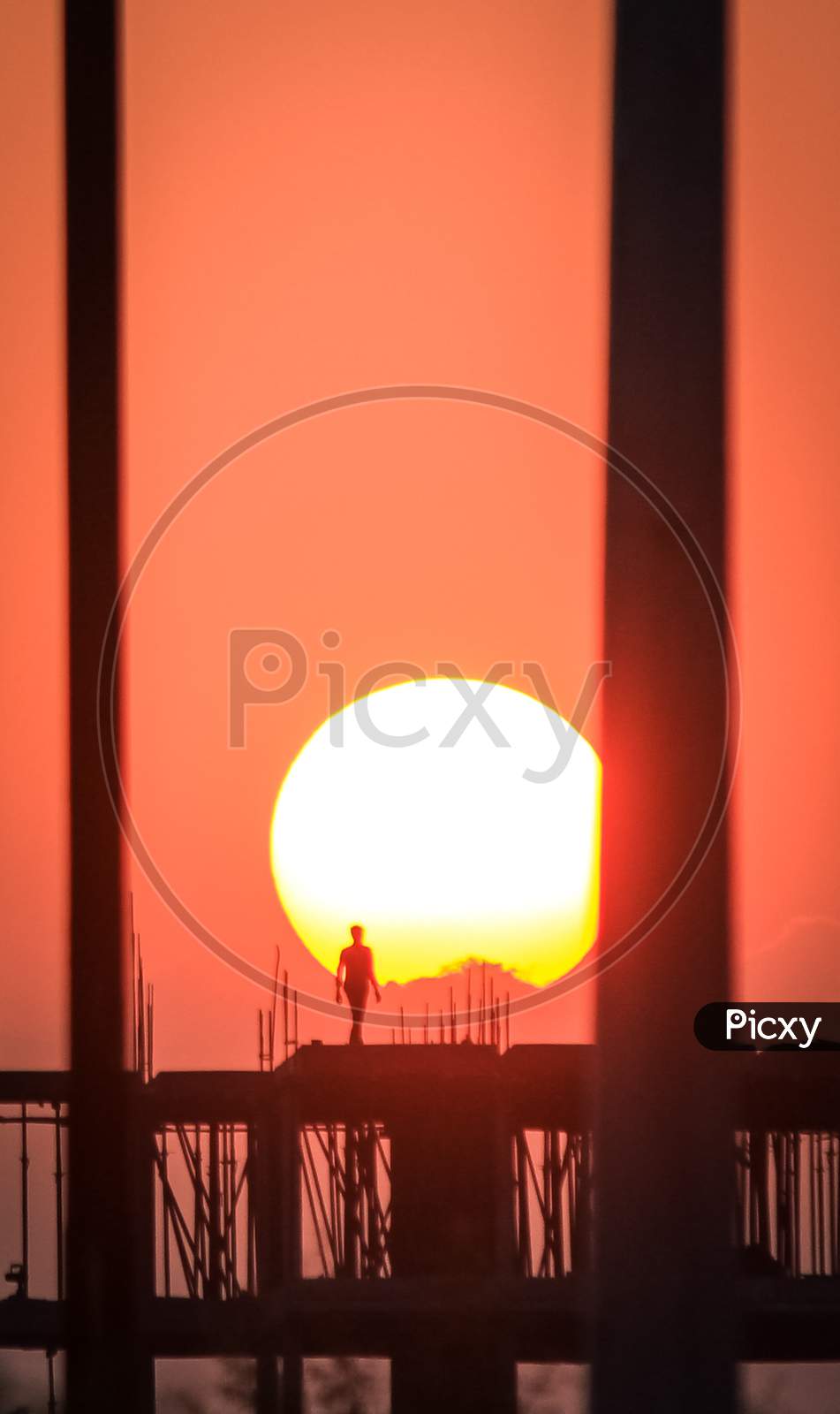 The beautiful sun and the man at the construction site , gives us a beautiful story of the sunset.