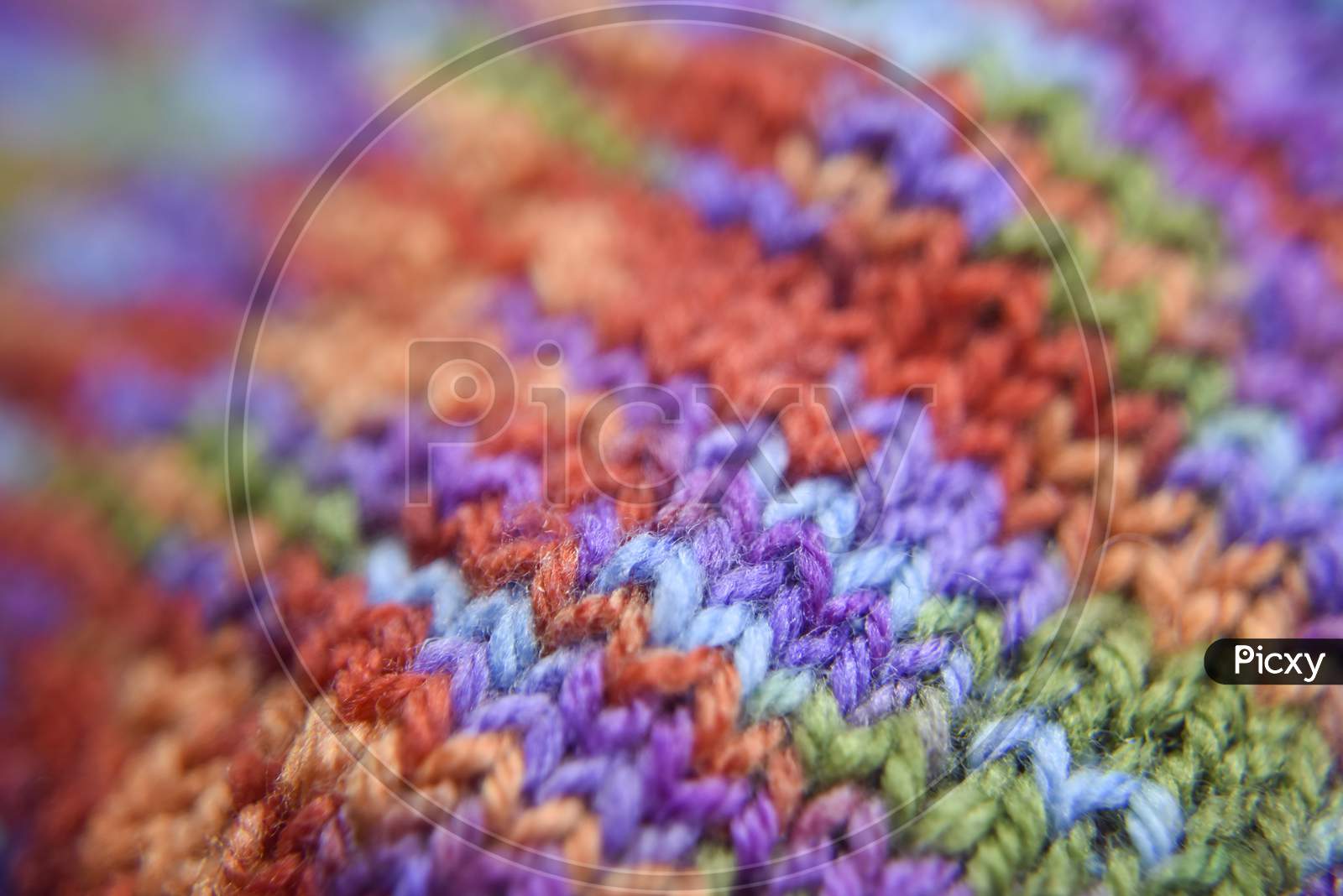 Selective Focus At The Bright Colorful Knitted Pattern Close-Up Look. Natural Wool Of Red, Orange, Green, Blue, Purple Colors.