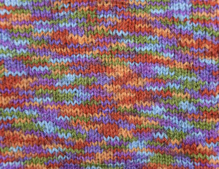 Bright Colorful Knitted Pattern Close-Up Look. Natural Wool Of Red, Orange, Green, Blue, Purple Colors.