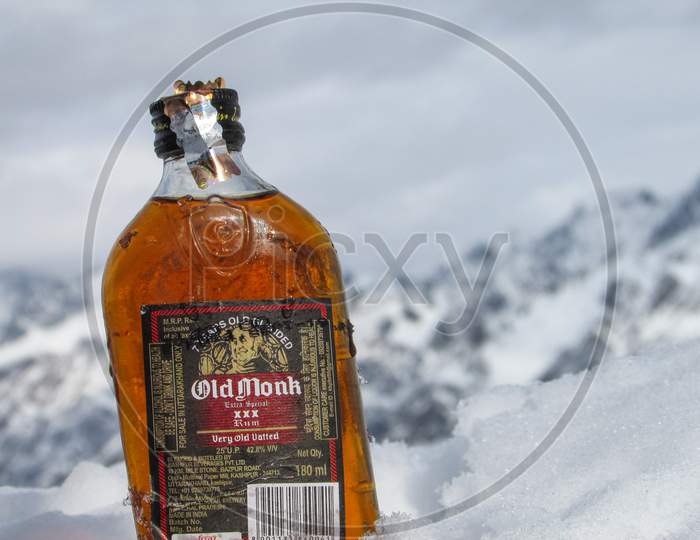 Old monk bottle in snow. 